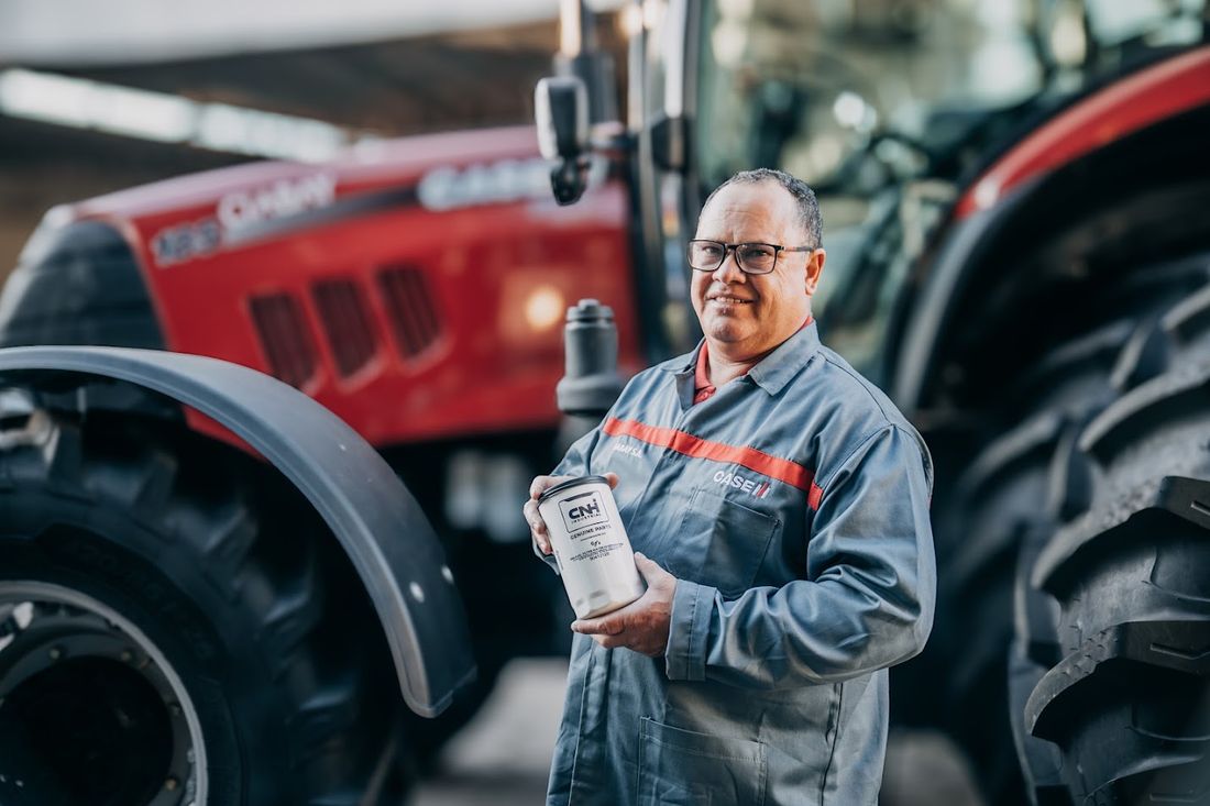 Colaborador de CIABAY mostrando un filtro CNH Genuine Parts frente a un tractor Case IH rojo