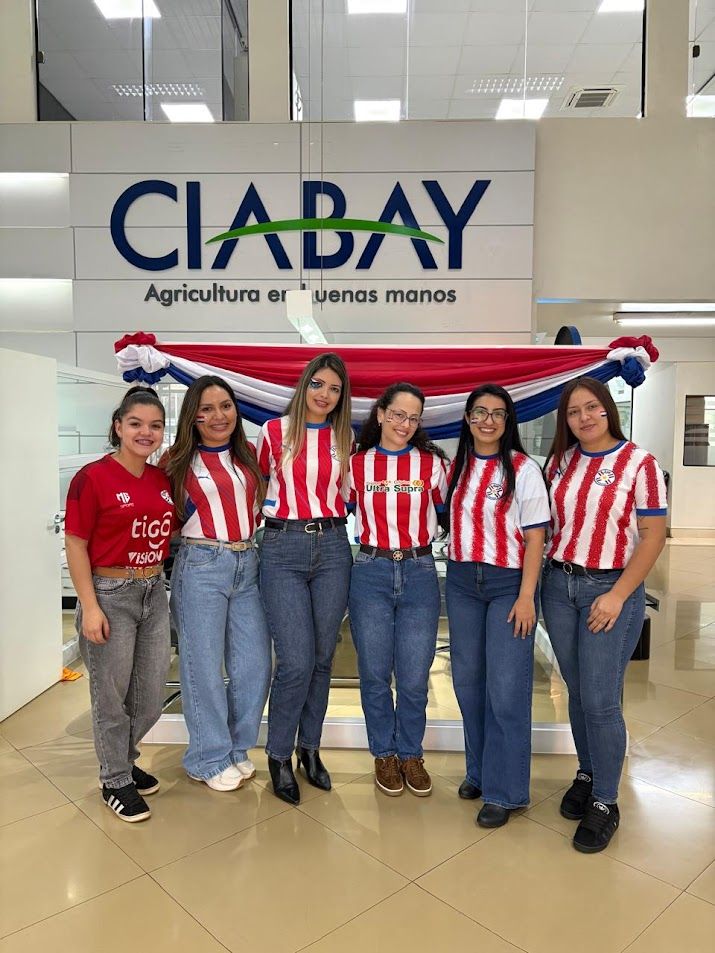 Colaboradoras de CIABAY con la albirroja frente al logo