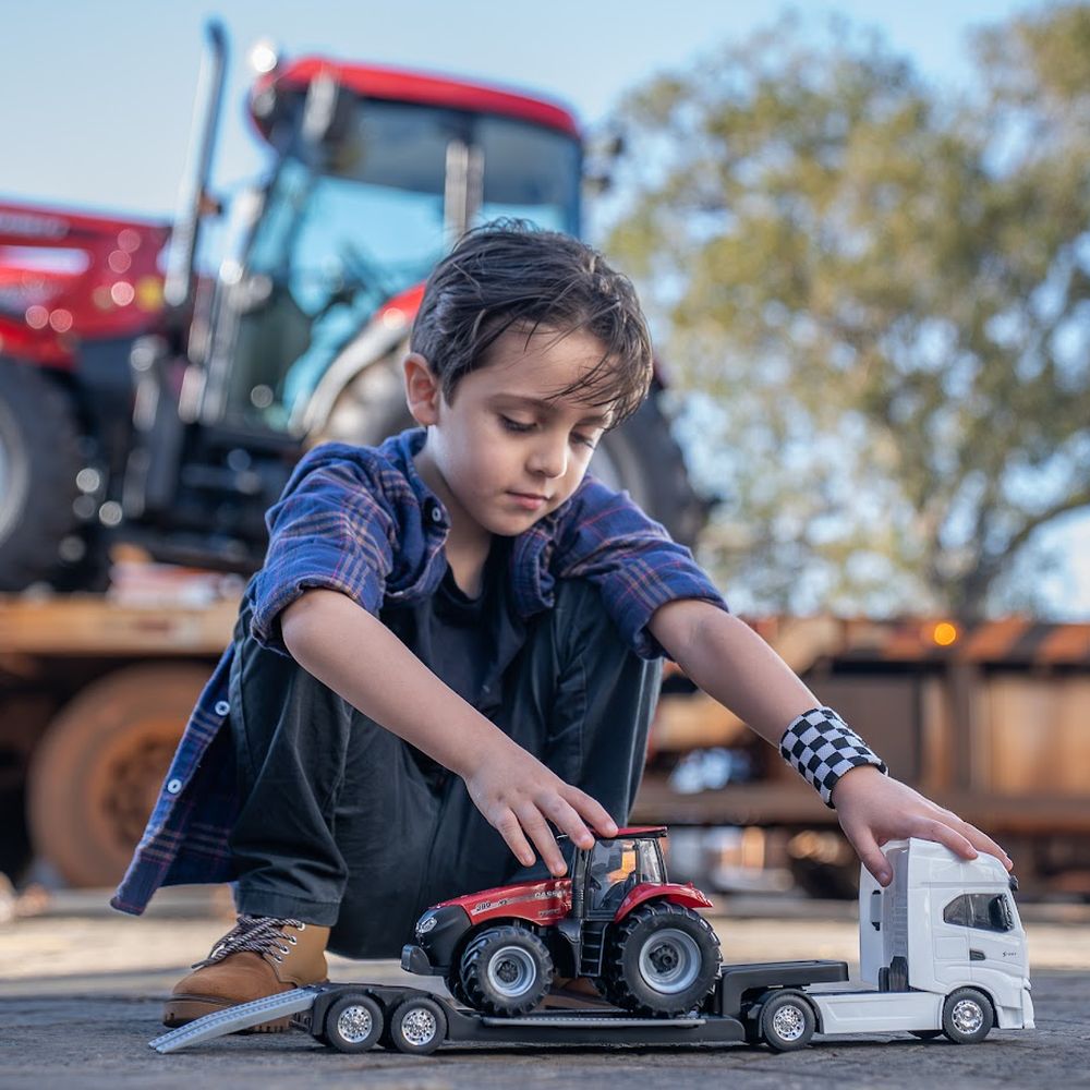 Niño jugando con un tractor Case IH a escala frente a un tractor real