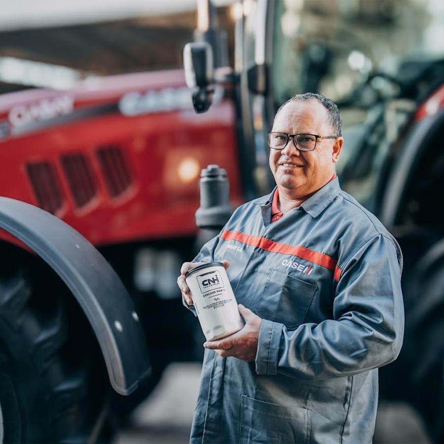 Técnico de post venta CIABAY con repuesto original CNH frente a un tractor Case IH