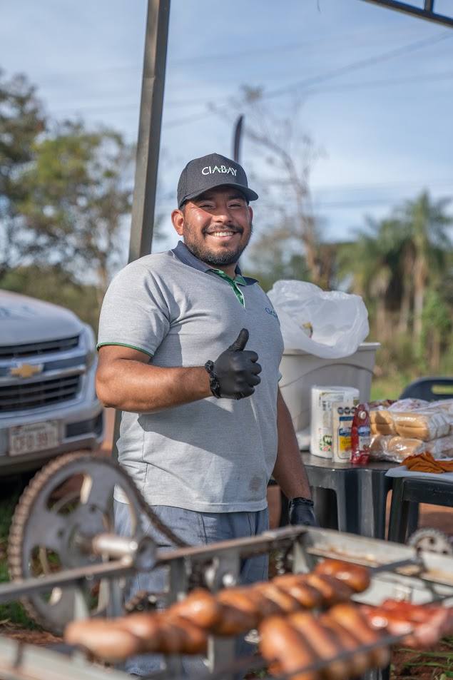 Colaborador de CIABAY sonriendo mientras prepara el asado del día de campo