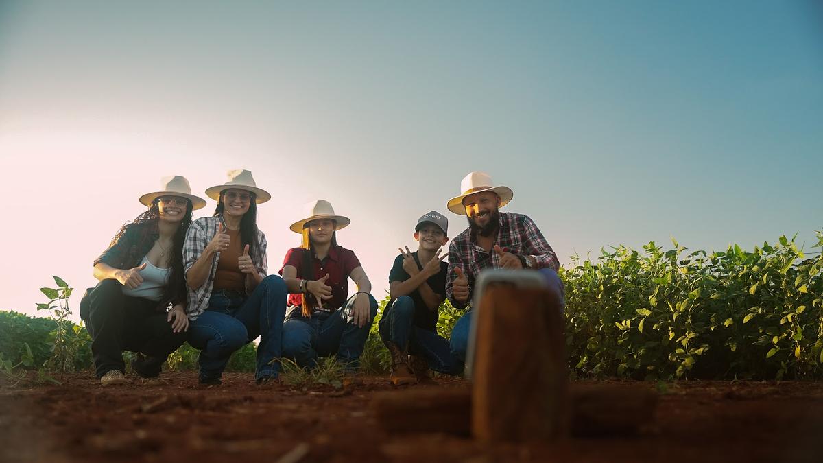 Familia productora posando entre los lotes de soja al atardecer