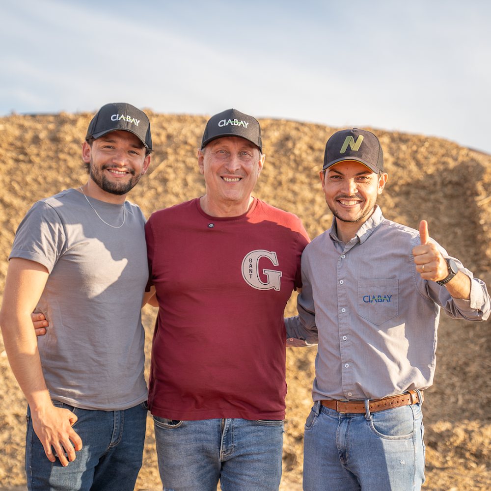 Productor junto a dos integrantes del equipo de CIABAY frente a un silo de maíz