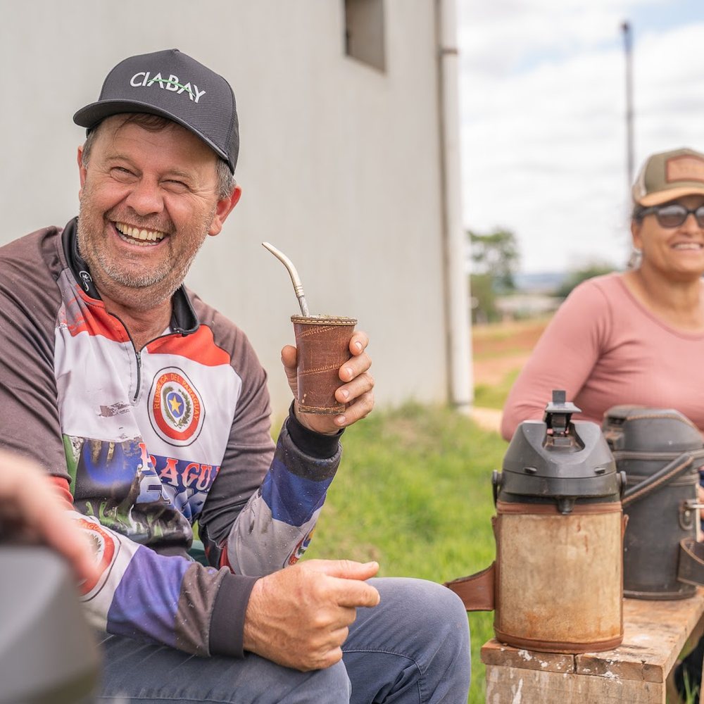 Productor riendo con su guampa de tereré y gorra de CIABAY, junto a los termos en una ronda de tereré